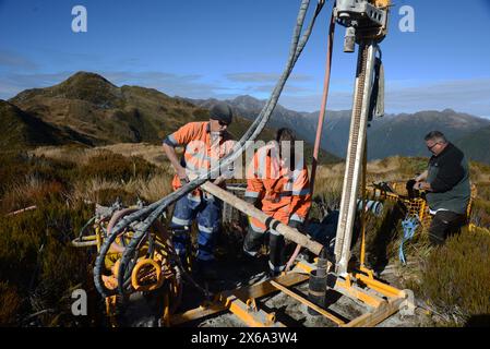 HAUPIRI, NUOVA ZELANDA, 7 MAGGIO 2024: I perforatori gestiscono un carro di perforazione portatile per affondare un foro di 10 metri sulla sommità del monte Morgan, affacciato sulla valle di Haupiri, West Coast, nuova Zelanda. Il foro verrà utilizzato per strumenti di monitoraggio GPS sismico per misurare il movimento lungo la faglia alpina che corre vicino alla base della montagna. Tutte le attrezzature di perforazione, tra cui un compressore d'aria, un generatore e un carro di perforazione, sono state portate in vetta in elicottero. Foto Stock