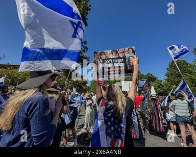 Palo alto, California, U.S.A. 12 maggio 2024. Bandiere israeliane e americane che volano e una donna ebrea con un cartello, "non dimenticare le loro facce: adolescenti in cattività'', e come centinaia di ebrei sono raggiunti da indù, musulmani, cinesi e altri alleati in un Counter-Rally presso l'Università di Stanford in occasione del giorno dell'indipendenza d'Israele e della festa della mamma in un raduno interreligioso organizzato da un gruppo studentesco ebreo. Questo era all'estremità di White Square, dove i manifestanti pro-palestinesi hanno allestito un accampamento di tende e hanno organizzato una manifestazione in cui hanno chiesto "Intifada” contro Israele, prendendo in giro gli ebrei Foto Stock