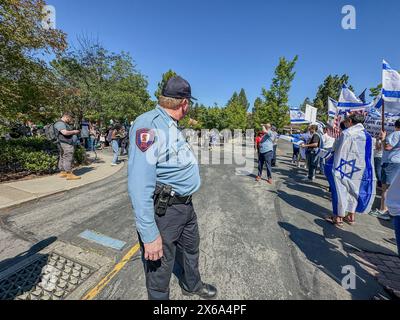 Palo alto, California, U.S.A. 12 maggio 2024. Centinaia di ebrei sono raggiunti da indù, musulmani, cinesi e altri alleati in un Counter-Rally presso l'Università di Stanford in occasione della festa dell'indipendenza di Israele e della festa della mamma in un raduno interreligioso organizzato da un gruppo studentesco ebreo. Questo era all'estremità della Piazza Bianca, dove i manifestanti pro-palestinesi hanno allestito un accampamento di tende e hanno organizzato una manifestazione in cui hanno chiesto "Intifada” contro Israele, hanno preso in giro gli ebrei e hanno dichiarato: "Vinceremo la guerra”. Un poliziotto tiene separati i due gruppi e si trova al centro tra di loro. (Immagine credito: Foto Stock