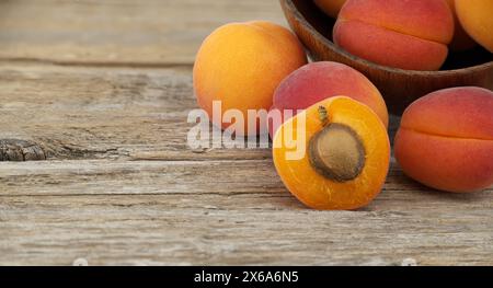 Collezione di albicocche intere mature e un taglio a metà per svelarne l'interno, tavolo rustico in legno Foto Stock