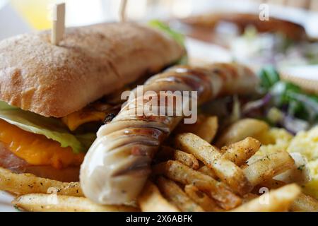 Panino con salsicce alla griglia e patatine fritte su un tavolo di legno Foto Stock