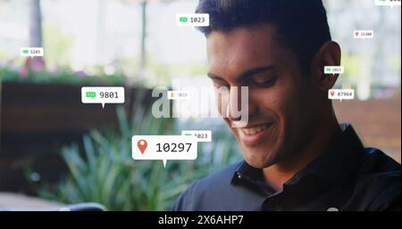 Immagine delle icone dei social media che fluttuano sopra un uomo caucasico sorridente mentre utilizza lo smartwatch Foto Stock