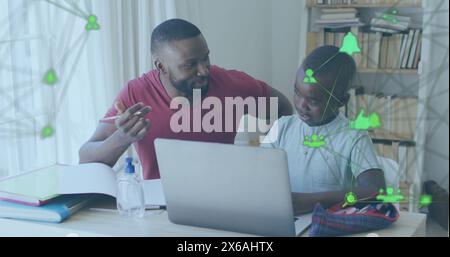In questa immagine, un padre afroamericano sta aiutando suo figlio con i compiti mentre è seduto a un tavolo Foto Stock