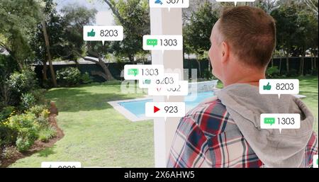 Immagine di icone dei social media che fluttuano sopra un uomo caucasico in piedi sul portico della casa Foto Stock