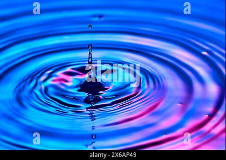 una goccia d'acqua che cade nell'acqua e crea onde Foto Stock