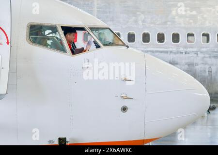 (240514) -- HAIKOU, 14 maggio 2024 (Xinhua) -- Un membro del personale di Grand China Aviation Maintenance Co., Ltd. (GCAM) opera all'interno della cabina di pilotaggio di un aereo in entrata in un hangar di una base di manutenzione di aeromobili a Haikou, provincia di Hainan, nella Cina meridionale, 13 maggio 2024. Un Boeing 737-800 della Jeju Air sudcoreana è stato recentemente sottoposto a manutenzione da parte della GCAM, che è anche l'ordine principale per la manutenzione di aeromobili in arrivo dalla Corea del Sud presso il porto di libero scambio di Hainan. La durata del servizio è prevista per circa 16 giorni, che possono beneficiare di trattamenti preferenziali del porto di libero scambio, compreso l'exem Foto Stock