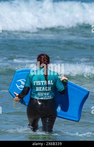 Un principiante di surf che si diverte durante una lezione di body boarding boogie boarding dalla Fistral Beach Surf School di Newquay in Cornovaglia nel Regno Unito. Foto Stock