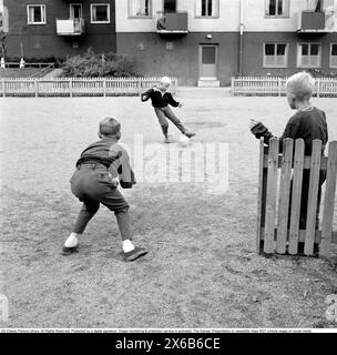 ragazzi degli anni '1950 che giocano a calcio. I bambini giocano a calcio nello spazio aperto del soggiorno. Il ragazzo sta per calciare la palla e segnare nel gol immaginario che è sorvegliato da un altro ragazzo. Roland Palm rif. 10-77-11 Foto Stock