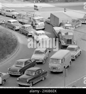 Guida negli anni '1960 Un incrocio in cui si formano auto provenienti da strade diverse e una coda di auto. Svezia 1962 Foto Stock