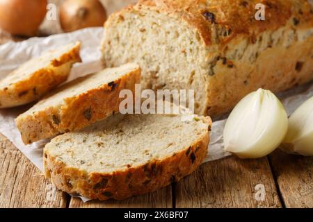 Pane alla cipolla appena sfornato, pane a fette, primo piano su pergamena su un tavolo di legno. Orizzontale Foto Stock