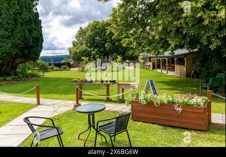 Caffetteria e tranquillo giardino all'interno dei Great Torrington Castle Community Gardens con muro di confine, ringhiere, scalini, alberi con vista rurale. Foto Stock