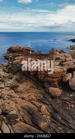 Riprese aeree con drone del Phare de Men Ruz Ploumanac'h Perros-Guirec Francia, il faro iconico in granito rosa arroccato su formazioni rocciose frastagliate Foto Stock