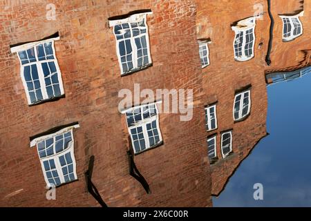 Riflessi leggermente distorti nell'acqua degli edifici in mattoni nel Birmingham Worcester Canal vicino al Diglis Basin nel centro di Worcester. Foto Stock