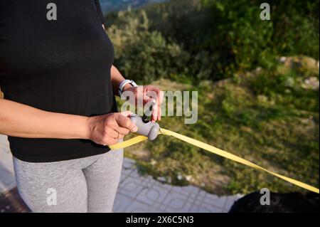 Donna che toglie sacchetti per rifiuti di animali domestici per dispenser sotto forma di ossa, pulisce feci, escrementi, beccucci mentre porta il suo cane a camminare all'aperto. Foto Stock