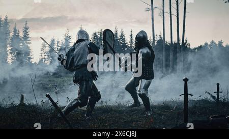 Epico Battlefield: Due cavalieri medievali corazzati che combattono con le spade. Guerra dell'Esercito del Medioevo. Azione Battaglia dei soldati guerrieri armati, uccidendo il nemico. Rievocazione storica cinematografica. Foto Stock