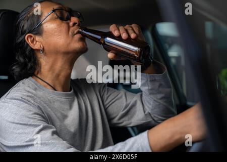 E' una cosa pericolosa da fare. Bere birra durante la guida è illegale e pericoloso. Foto Stock