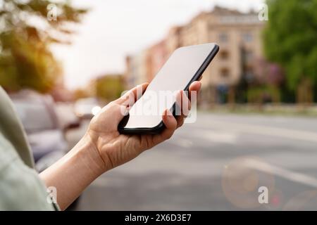 Telefono cellulare con schermo tattile in primo piano con la mano della donna sulla strada della città. Foto Stock