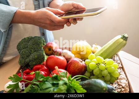 Persona che acquista online verdure biologiche coltivate in azienda utilizzando il telefono cellulare. ordinare e consegnare prodotti alimentari tramite internet. Foto Stock
