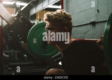 Primo piano di un atleta crossfit che fa squat da barbell in palestra Foto Stock