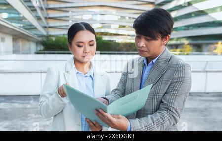 Due persone aziendali che esaminano la cartella all'esterno dell'edificio dell'ufficio Foto Stock