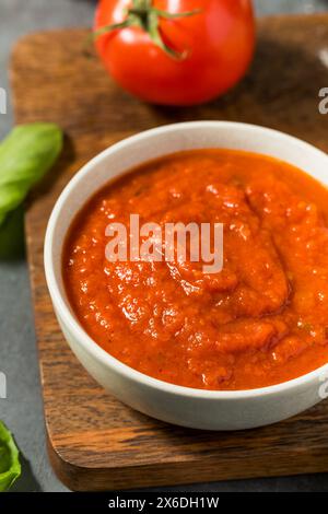 Salsa di pomodoro biologico crudo rosso per pizza in ciotola con basilico Foto Stock