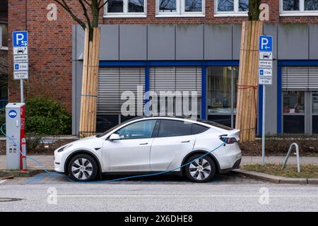 amburgo, Germania - 01 23 2024: Vista di una e-car bianca parcheggiata e in carica in un parcheggio per auto elettriche Foto Stock