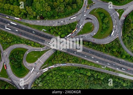 Vista aerea direttamente sopra un importante svincolo autostradale del Regno Unito con rotatoria e ponte che attraversano boschi verdi in un concetto di problema ambientale Foto Stock