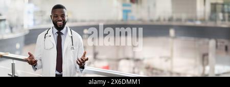 Ritratto di allegro bel medico nero in posa in clinica Foto Stock