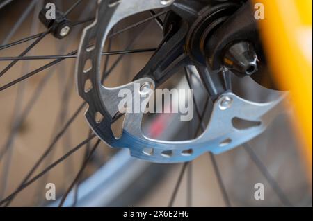 Primo piano del freno a disco di una bicicletta su una ruota con vista dettagliata del rotore del freno e delle razze, su uno sfondo sfocato Foto Stock