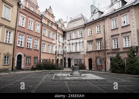 Piazza con architettura tipica in una giornata invernale nel centro di Varsavia, Polonia nell'Europa orientale. Al centro c'è una grande campana Foto Stock