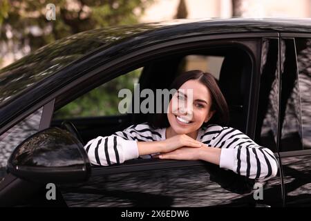 Giovane donna seduta dentro la sua auto moderna Foto Stock