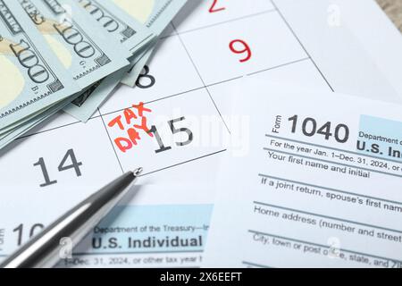 Giorno fiscale. Calendario con promemoria della data, documenti, banconote in dollari e penna sul tavolo Foto Stock