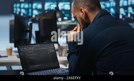 Scienziato informatico che supervisiona i server dei data center, digita il codice sui notebook, risolve i problemi dei sistemi. Professionisti del software che eseguono la manutenzione su mainframe tramite notebook, primo piano Foto Stock