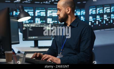 Scienziato informatico che supervisiona l'hub del server, digita il codice sul PC, risolve i problemi dei sistemi. Professionisti del software che si occupano di manutenzione su supercomputer, sistemi di rete e array di storage Foto Stock