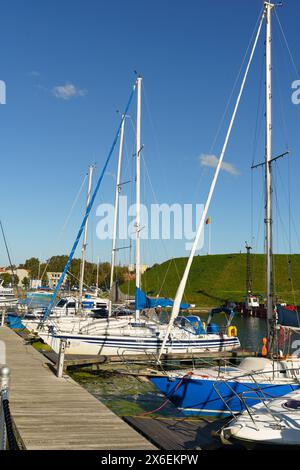 Klaipeda, Lituania - 11 agosto 2023: Un gruppo di barche a vela è assicurato su un molo, i loro alberi raggiungono il cielo mentre riposano in acque calme. Foto Stock