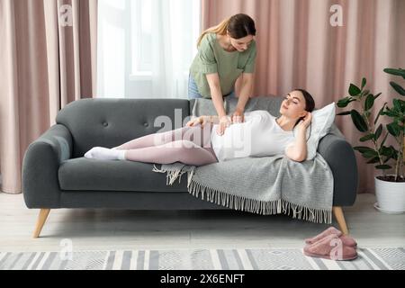 Doula si prende cura delle donne incinte a casa. Preparazione alla nascita del bambino Foto Stock