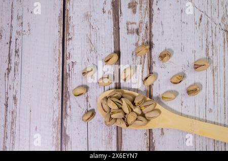 noci miste in cucchiaio di legno bianco. Mix di noci varie su sfondo colorato. pistacchi, anacardi, noci, nocciole, arachidi e noci del brasile. Foto Stock