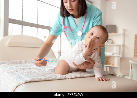 Pediatra donna che fa un'iniezione sul divano in clinica Foto Stock