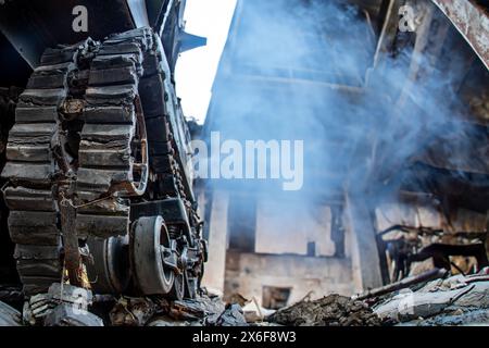 Un carro armato danneggiato si trova tra le rovine di una casa Foto Stock