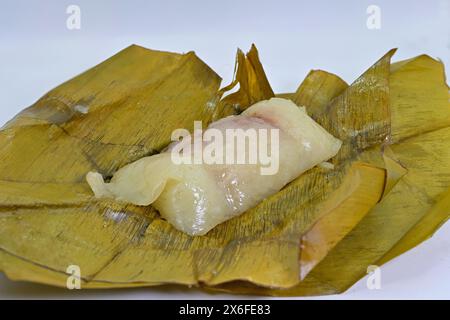 Khao tom mat, un popolare dolce tailandese fatto di riso glutinoso o appiccicoso al vapore, srotolato, su foglie di banana Foto Stock