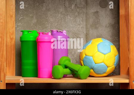 Ripiani con diverse attrezzature sportive contro il muro verde Foto Stock