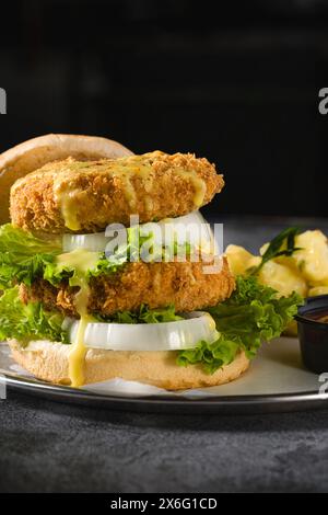 Doppio hamburger di pesce con insalata di patate su un piatto di metallo Foto Stock