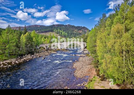 Old Bridge of Dee o Invercauld Bridge vicino alla strada principale da Braemar a Ballater, con cielo blu sul fiume e alberi all'inizio della primavera Foto Stock