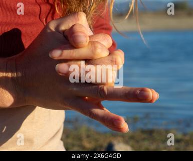 Mani di donna che fanno un mudra in natura con un lago alle spalle Foto Stock