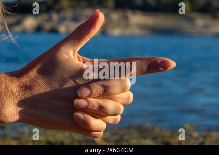 Mani di donna che fanno kali mudra in natura con un lago alle spalle Foto Stock