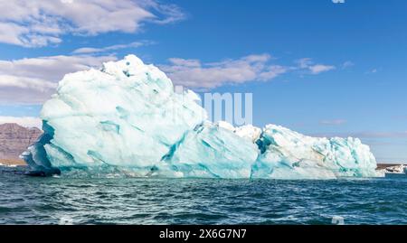 Un grande blocco di ghiaccio blu che galleggia nell'oceano. Il cielo è limpido e blu Foto Stock