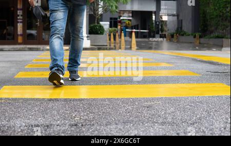 Uomo che attraversa la strada usando la zebra gialla. Concetto di sicurezza stradale. Foto Stock
