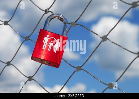 una singola serratura rossa a forma di amore con una coppia e un bambino è appesa su una ringhiera del ponte Foto Stock