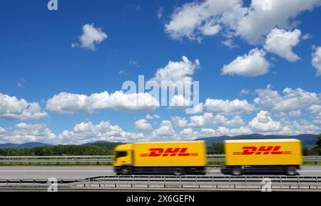 Un camion giallo con logo DHL viaggia su un'autostrada vicino a Deggendorf con la foresta bavarese sullo sfondo, bassa Baviera, Germania Foto Stock