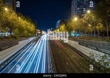 Vista notturna panoramica del Paseo de la Castellana avenue nella città di Madrid, Spagna, Europa. Si possono vedere le strisce di luce delle auto che passano Foto Stock